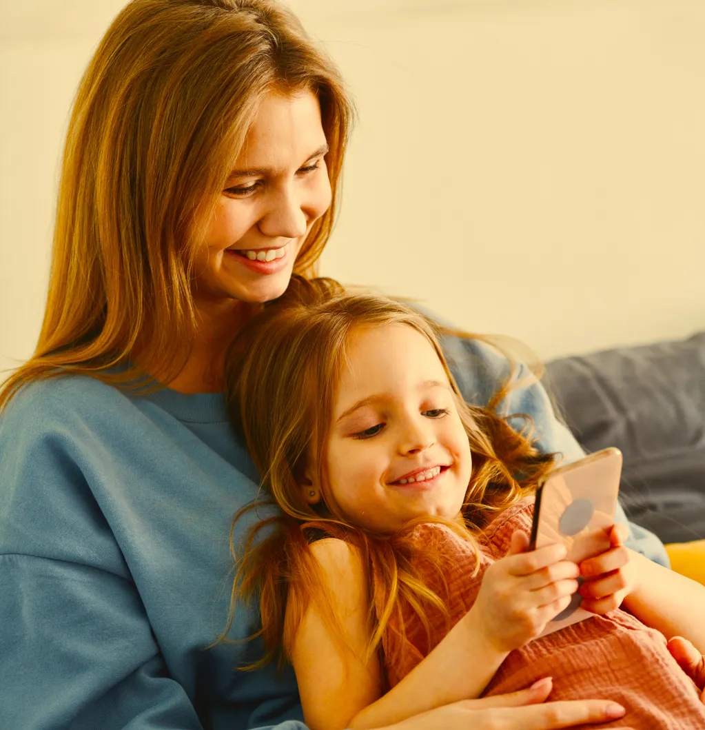 Mãe e filha sorrindo olhando para o celular